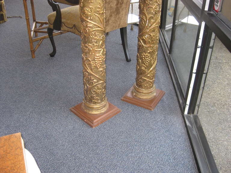 Great looking pair of giltwood columns with grape leaves and grapes design.  These are attached to modern wood square bases to stabilize them. The tops are  about 9