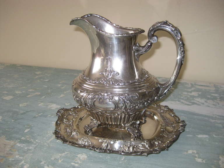 Rare 56 Oz Sterling Silver water pitcher with tray made by Gorham.  Covered in swags with fruit, flowers and bows.  This was retailed by William Wise and Son in the late 19th or early 20th C.  The tray is  11.5 wide 10.5 deep and 1' high it weighs