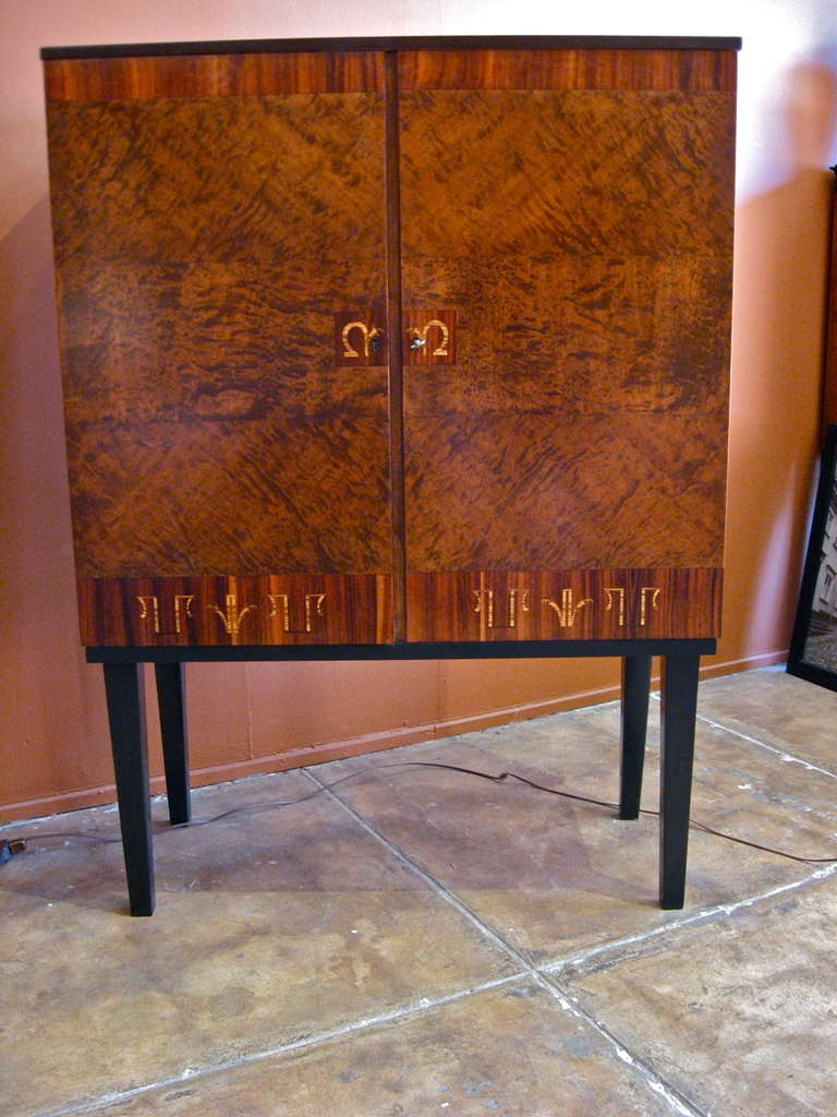 Swedish art deco inlaid cabinet made at Mjolby Intarsia ca. 1930. Doors in flame birch, zebrano, ebony and rosewood. Base in Ebonized birch wood. Interior is composed of two golden birch wood storage cavities with removable and adjustable shelves.