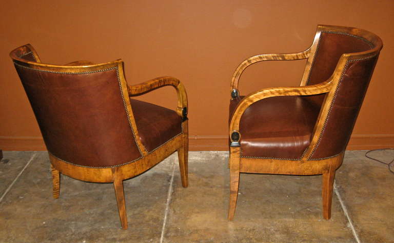 Pair of Swedish Art Deco barrel back (ca. 1920) Neo-Classical/Biedermeier Revival armchairs.
Rendered in highly figured golden flame birch wood with ebonized detailing. 
Restored and recovered in brown leather.

The price listed is the FINAL NET