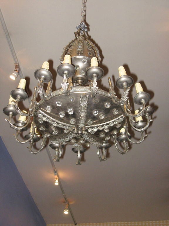 Argentine mid-twentieth century fifteen arm chandelier in nickel. The fixture is encrusted with clear round cut crystals. The fifteen bulb bases take chandelier base bulbs.  In very good original antique condition.

