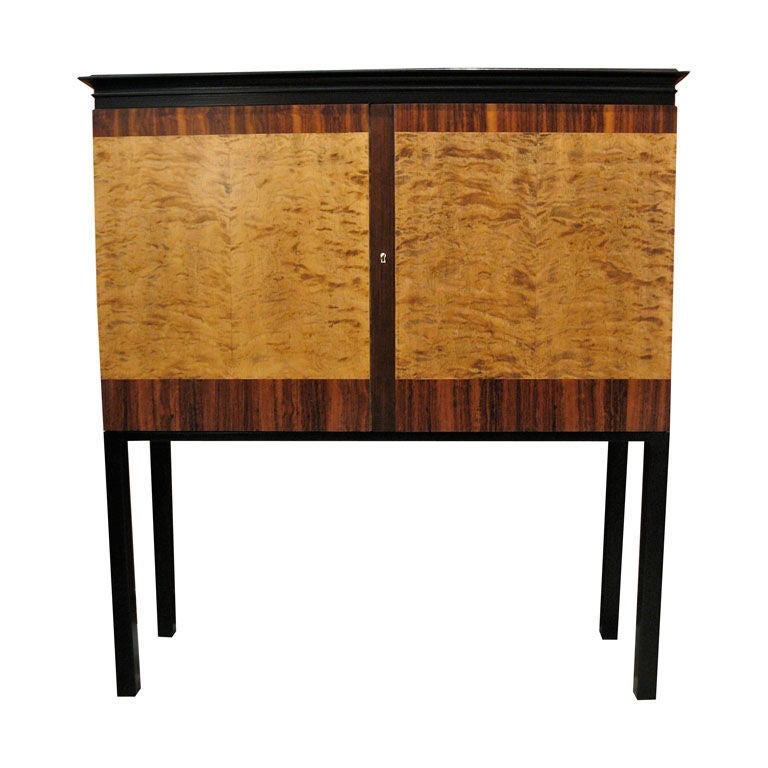 Swedish Art Deco storage cabinet/dry bar/sideboard in highly figured golden flame birch and rosewood with ebonized birch base and top. There is no partition in this cabinet making it perfect for television storage. The two original shelves are