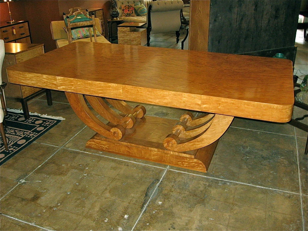 Art deco dining table in highly figured golden flame birch wood.<br />
Six modernist arms secure base to top. Completely restored.