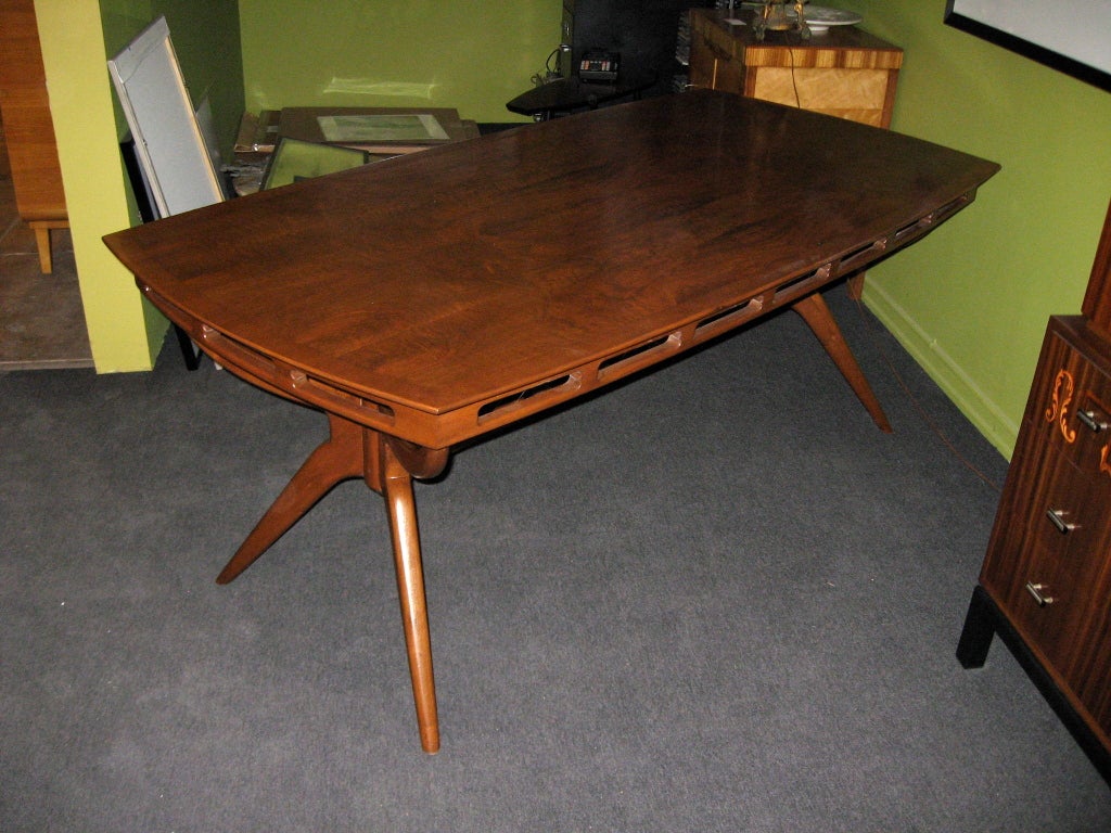 Argentine mid-century modern dining table in walnut with highly figured, book-matched walnut top. Tripod style legs. Top is a soft rectangle. Crafted at Bonta, Buenos Aires ca. 1950.

The price listed is the FINAL NET price, which reflects a 50%