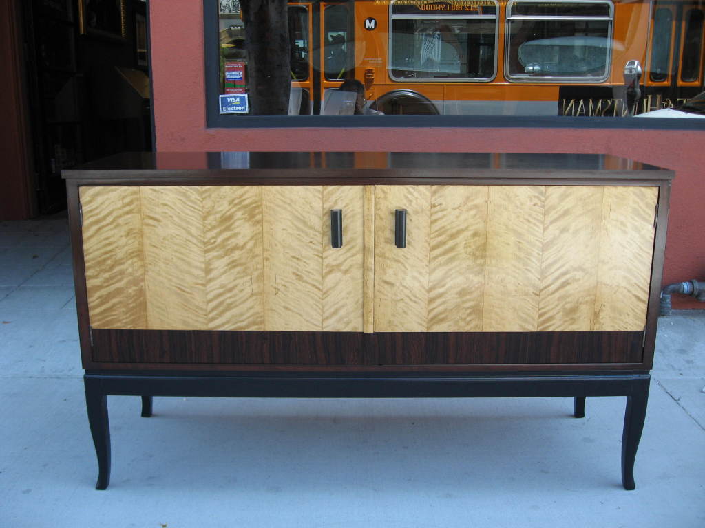 Swedish art deco era sideboard composed of highly figured golden flame birch with rosewood banding. Base in ebonized birch wood. 
Cabinet in stained birch wood. Pulls in ebonized birch wood. 
Single cavity interior cabinet with removable