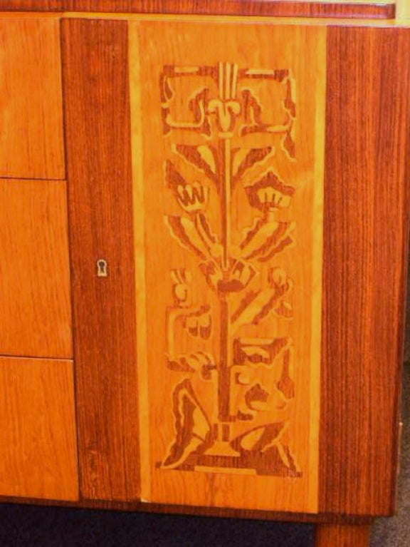 Exceptionally inlaid Swedish Art Deco era bar/storage cabinet in rose wood, birch and elm. This piece has three drawers with brass pulls and two side cabinets with removable shelves. When the shelves are removed the two side cavities are perfectly