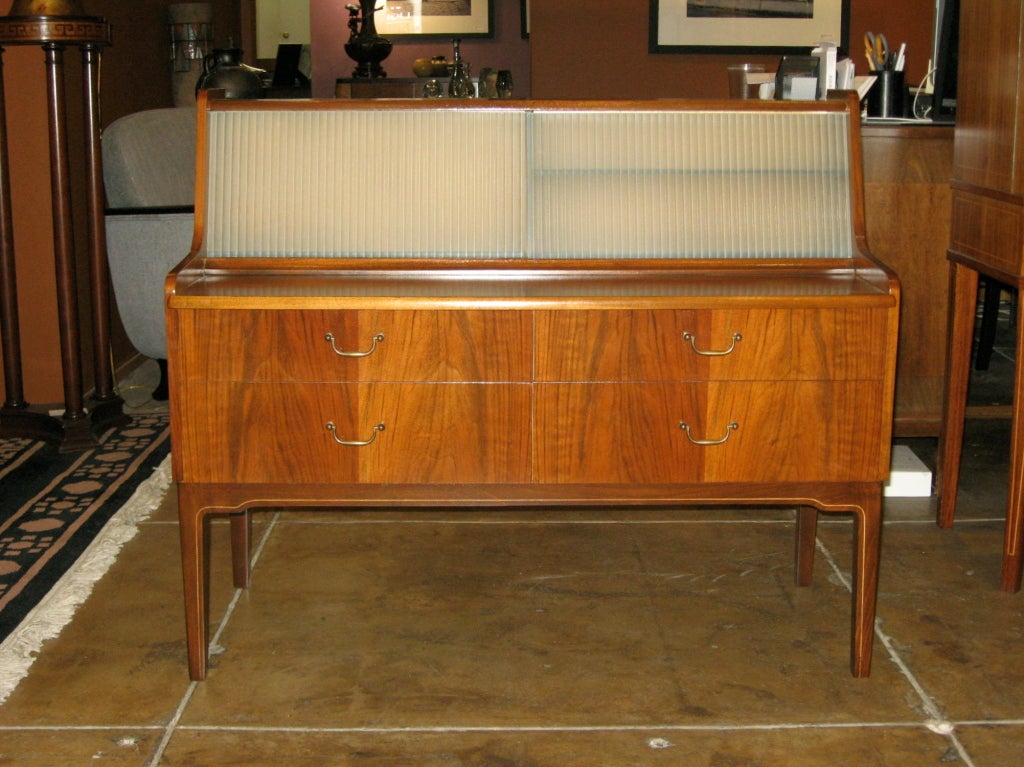 Swedish mid-century Modern dresser/bar/storage cabinet in Walnut with inlaid birch fillet. Sandblasted glass sliding doors. Four drawers with metal pull-handles. Shelve pulls out for use as table/tray.

The price listed is the FINAL NET price,