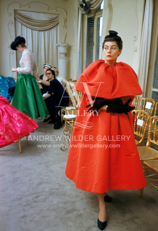 A magical moment is captured by photographer Mark Shaw in the salon of Balenciaga in Paris,1954. Here a model poses for American buyers from I Magnin department store in Balenciaga's signature Orange Coat. This image is an outtake from an assignment