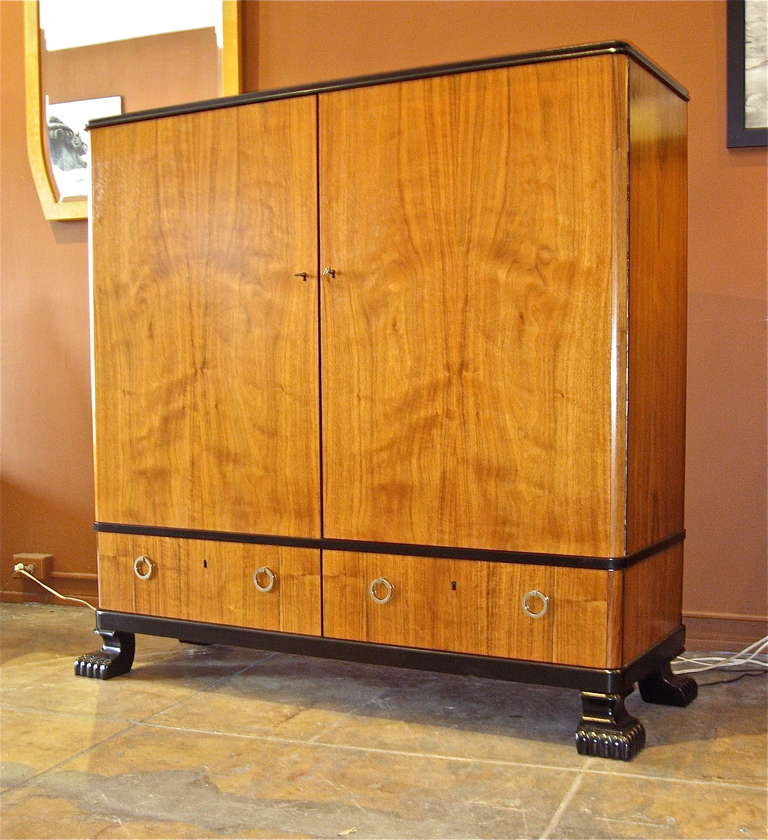 Swedish art deco era storage cabinet. Exterior in highly figured walnut and ebonized birch wood. Two exterior drawers. The interior contains adjustable shelves as well as drawers. Four ebonized modernist claw feet. Original drawer pulls in bronze.