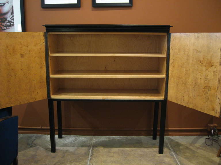 Swedish Art Deco storage cabinet/dry bar/sideboard in highly figured golden flame birch and rosewood with ebonized birch base and top. There is no partition in this cabinet making it perfect for television storage. The two original shelves are