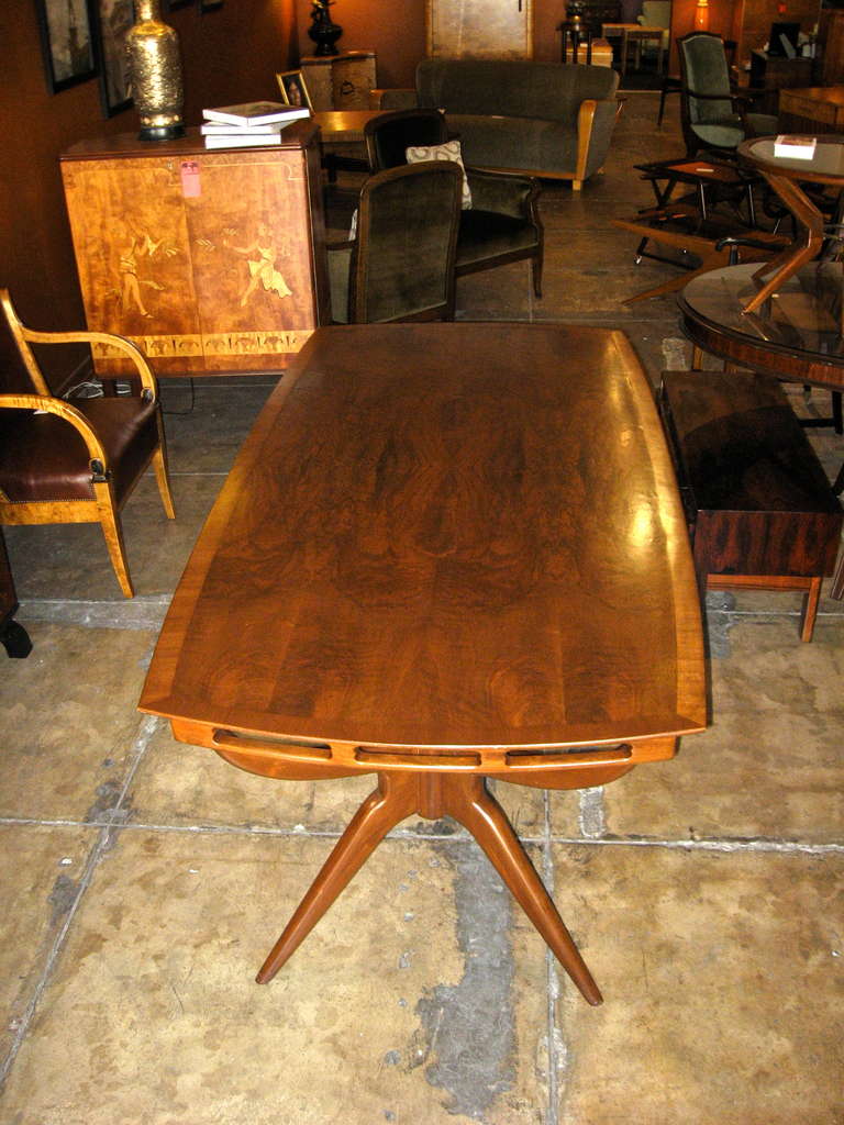 Argentine mid-century modern dining table in walnut with highly figured, book-matched walnut top. Tripod style legs. Top is a soft rectangle. Crafted at Bonta, Buenos Aires ca. 1960. This table has been completely restored by our craftsmen.
The