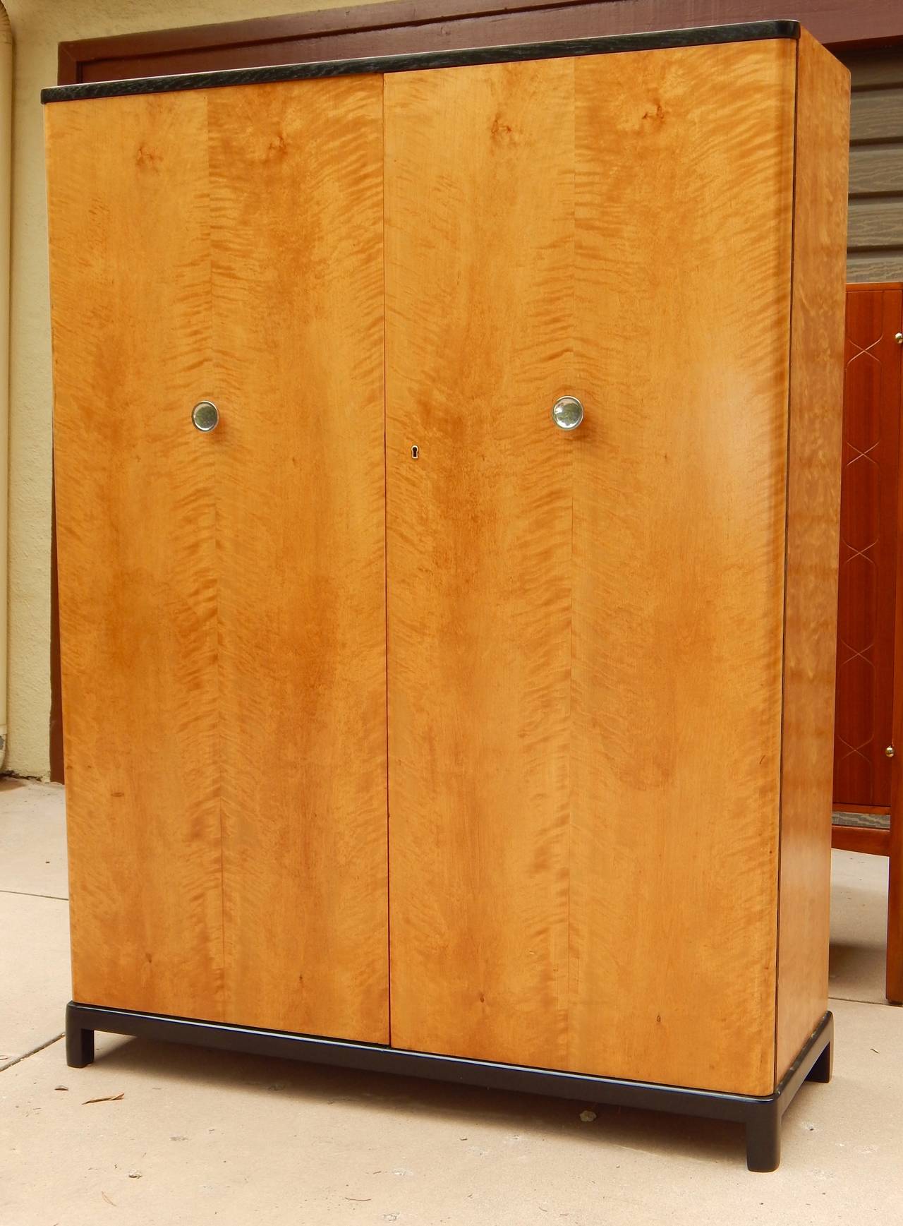 Swedish Art Deco era storage cabinet in highly figured, bookmatched golden flame birchwood. Interior composed of sliding drawers and adjustable shelves. There are six original shelves (photographed here stacked, not hung). Original knobs in polished