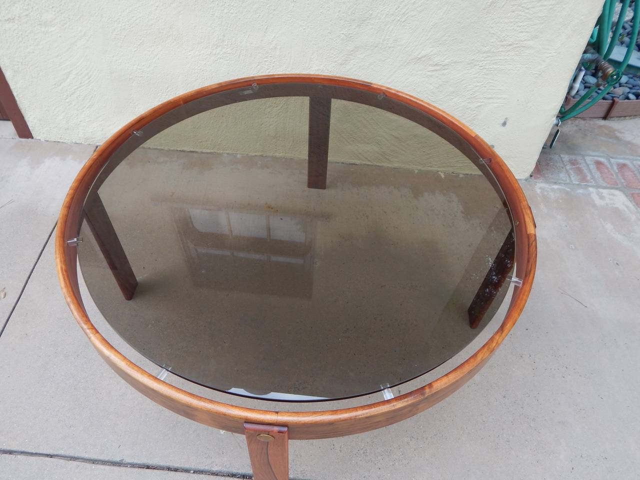 Danish rosewood coffee table with smoked glass top.
Original glass top is floated on Lucite pegs. There are brass fittings which hold each rosewood leg in place. Made in Denmark, circa 1970.