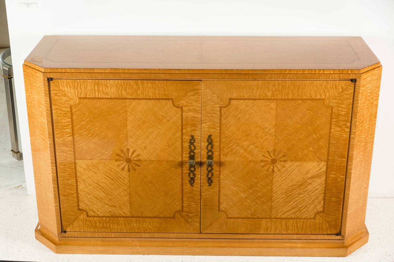This is a rare example of Tommi Parzinger's work using fine veneers. This cabinet has absolutely stunning book matched veneers of Curley Maple inset with Mahogany inlays. Perfect from every angle, it is hard to imagine the work that went into