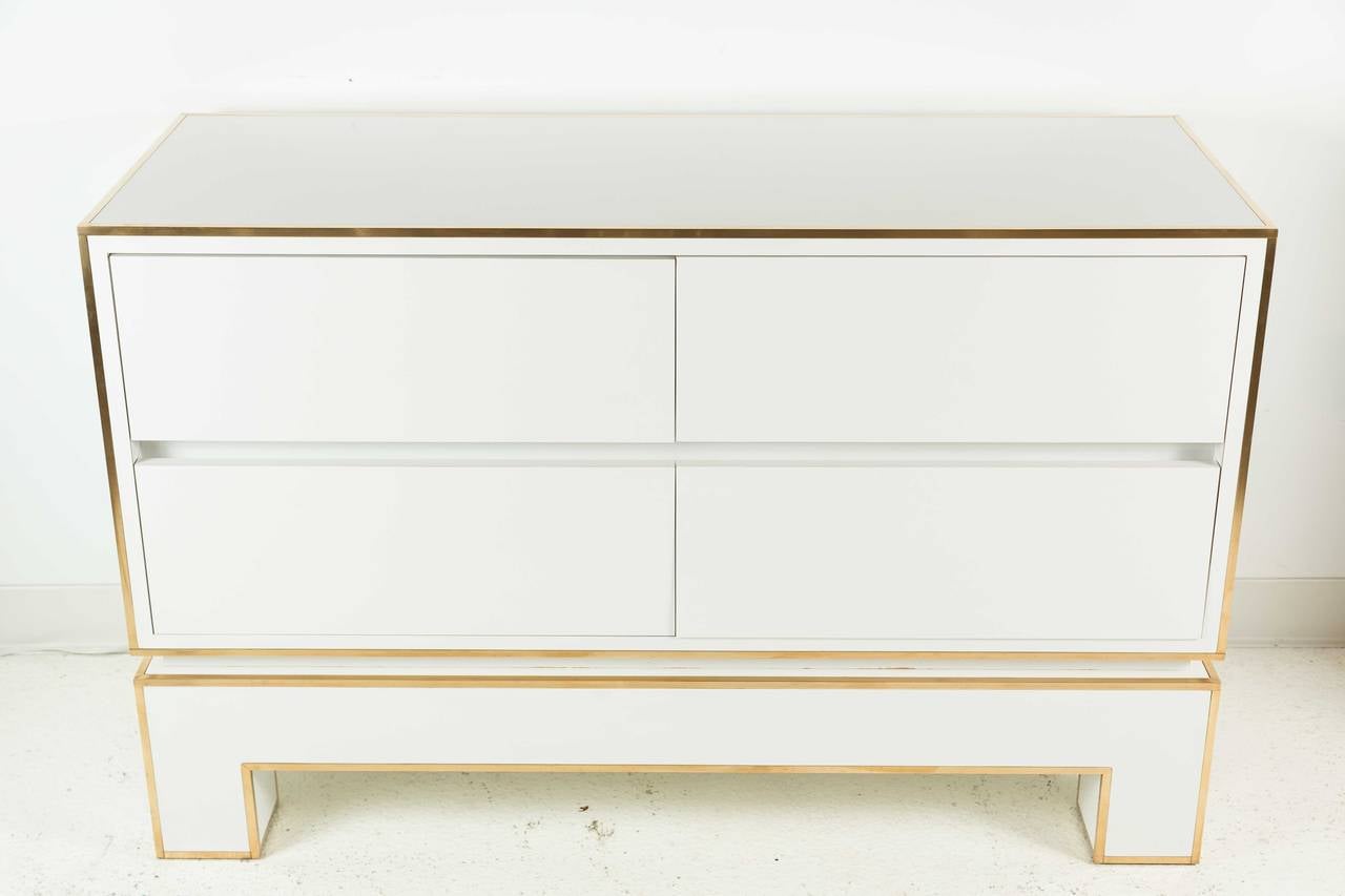 Chic, white gloss laminate chest of drawers with brass inlay around edges. Piece is from a series by Alain Delon for Maison Jansen and was manufactured by Mario Sabot in Italy, in 1972. Chest has four drawers, each 8