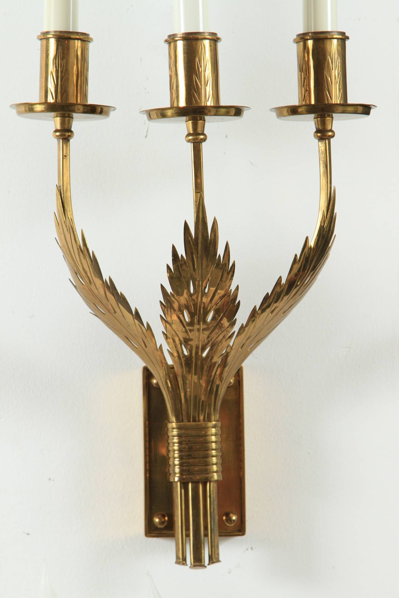 Lovely and elegant group of brass candelabra sconces featuring an acanthus leaf motif were designed by Tommi Parzinger from one of his most important  commissions, the Appleman residence in Ocean, New Jersey.  Leaf design is also imprinted on each