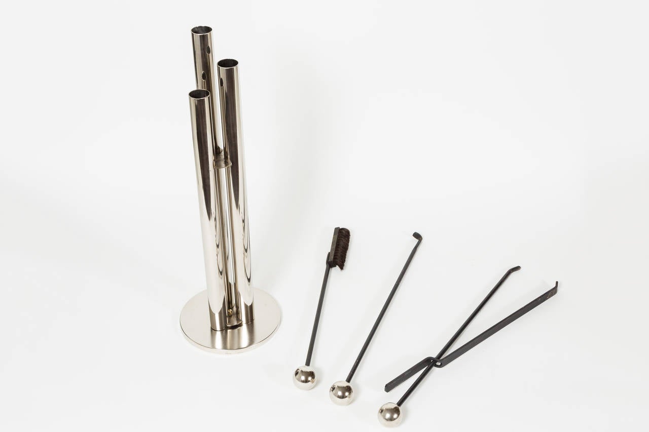 Sleek set of polished stainless steel and black iron fireplace tools. Base is in a matte finish. Each of the three tools is accentuated by a sphere and neatly concealed within the sculptural cylinders of the outer housing. Set includes a brush,