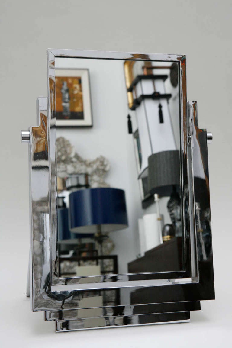 A chic Art Deco style polished chrome tabletop mirror in the style of La Maison Desny. The mirror pivots to allow for the perfect angle and the stand on the back is fixed.  This faithful copy of Desny's mirror was no doubt made during the 1970's