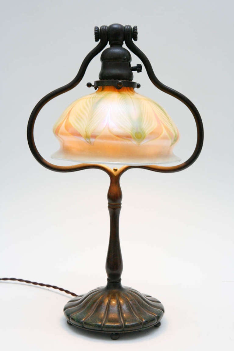 A stunning table lamp with a Tiffany Studios Cast bronze base and a pulled feather iridescent shade. The base is stamped 