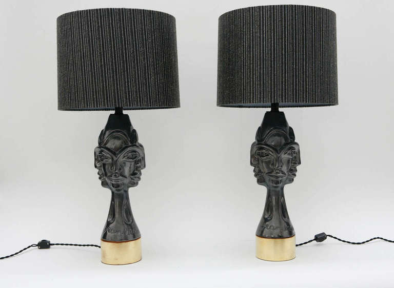 A striking pair of gunmetal glazed sculptural works, signed Jean Marais, that were later converted to table lamps. The ceramics have been set atop gold leafed wood bases and have custom black silk shades overlaid with Lurex casement.