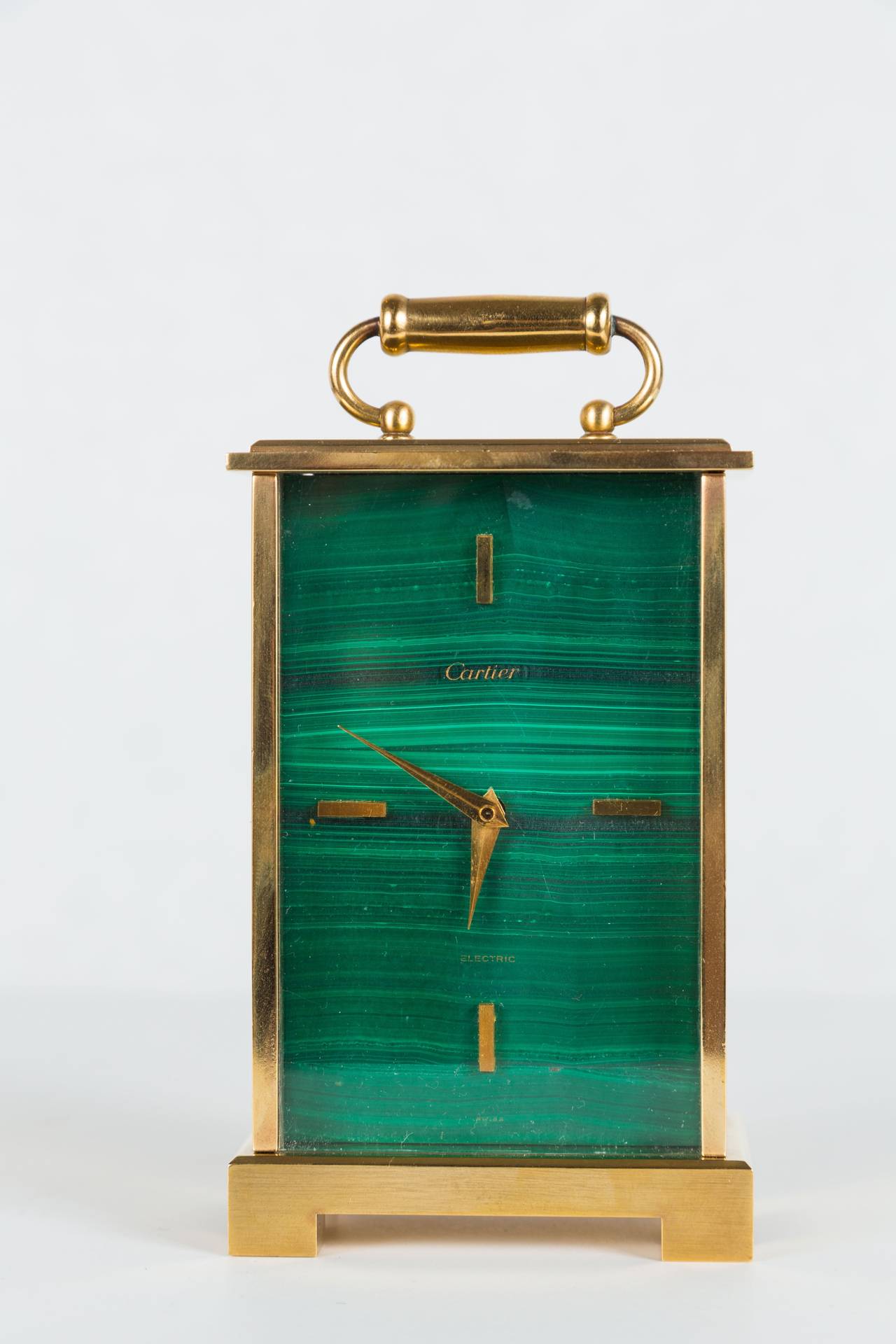 Handsome Art Deco carriage style desk clock by Cartier in brass with brass details and a malachite face. Clock is battery operated, but it appears the movement has been replaced at some point. 

Height of case is 4 7/8