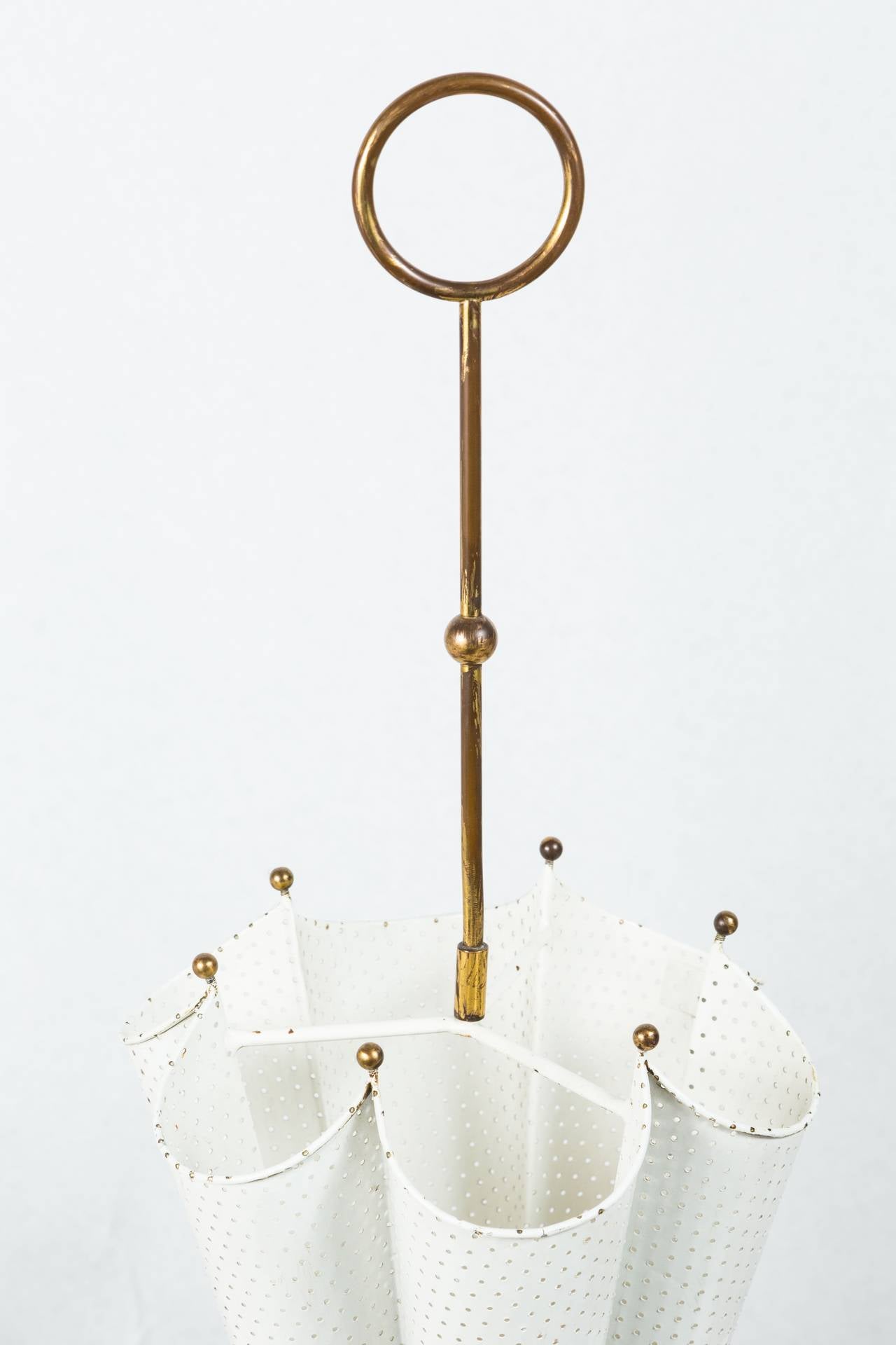 Wonderful painted metal umbrella stand with brass details. Design is of an upside down umbrella and features white painted perforated metal with brass details. A brass acanthus leaf gracefully covers the base and the 