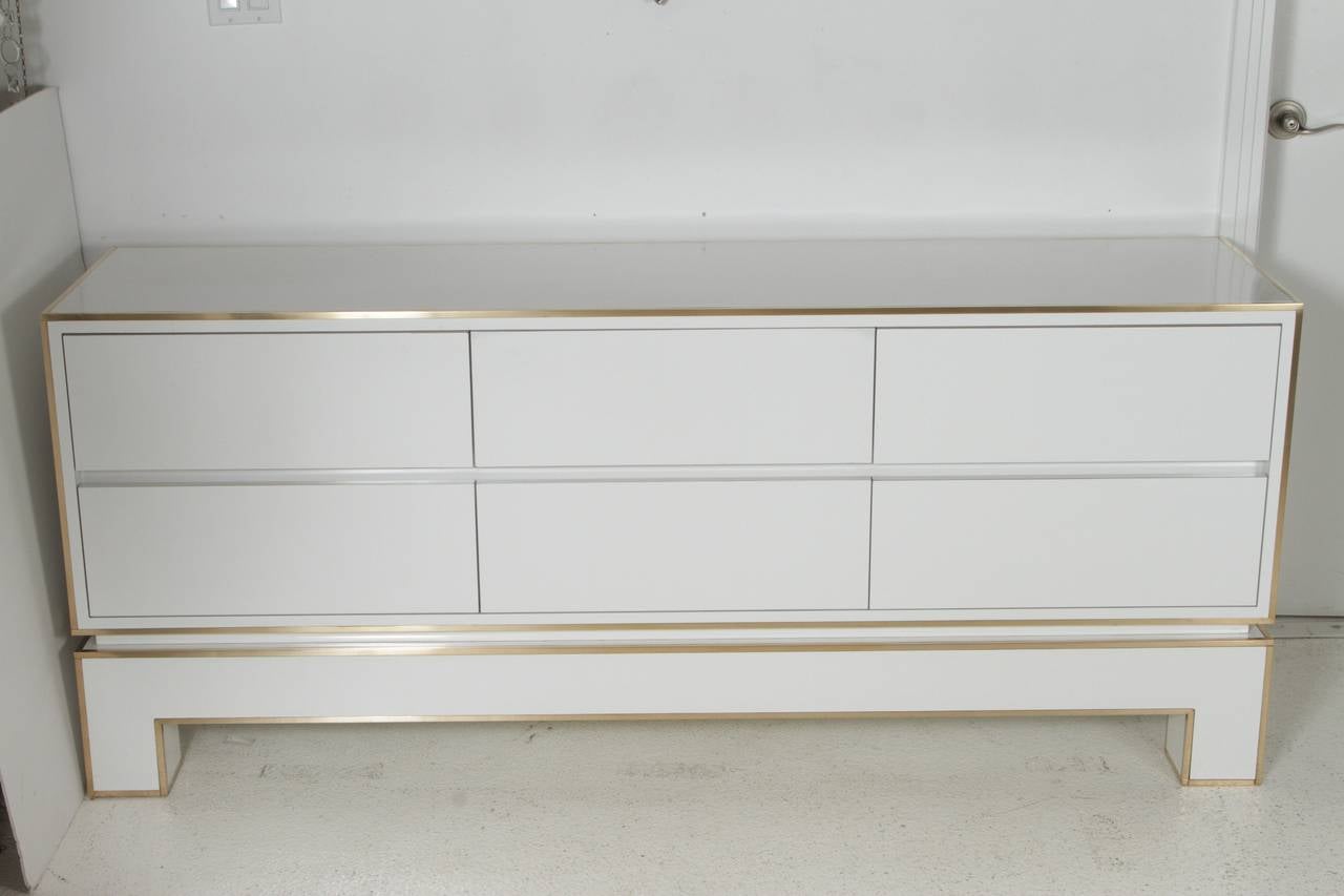 Chic, white gloss laminate large chest of drawers with brass inlay around edges. Piece is from a series by Alain Delon for Maison Jansen and was manufactured by Mario Sabot in Italy, in 1972. Chest has six drawers, each 8