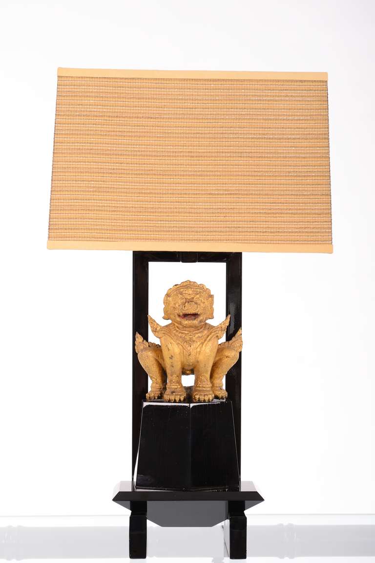 A striking table lamp featuring a carved and giltwood Foo Dog set on a lacquered armature base. Custom designed by William Haines for the Beverly Hills estate of Dr. Herbert and Mrs. Rita LeRoy Roedling. This lamp is an excellent example of Haines's