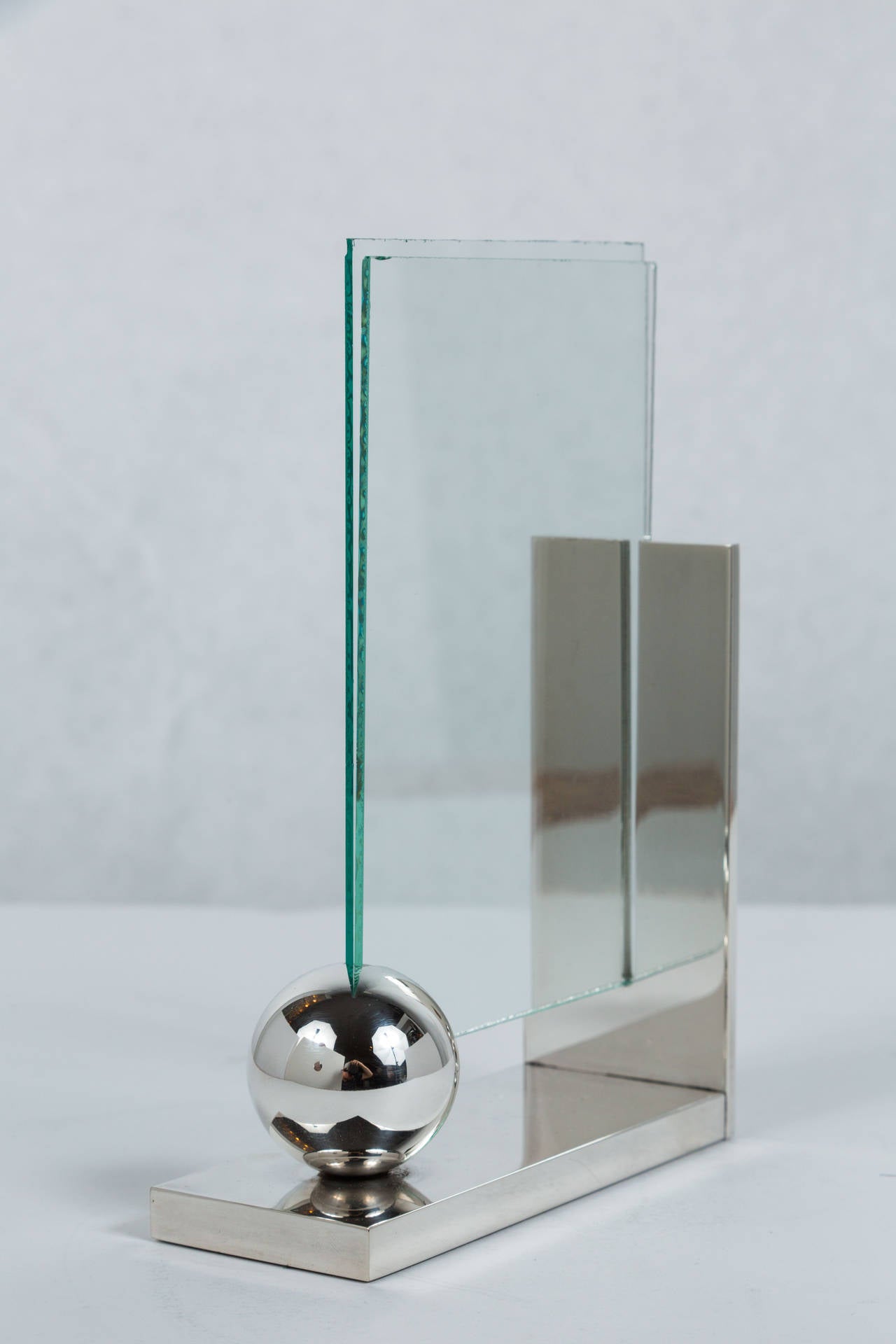 Elegant and simple silver plate frame with two floating pieces of glass to add a picture in. The glass is held upright by the back vertical detail and sphere on the front. Glass has minor nicks but can easily be replaced, as it slides entirely out