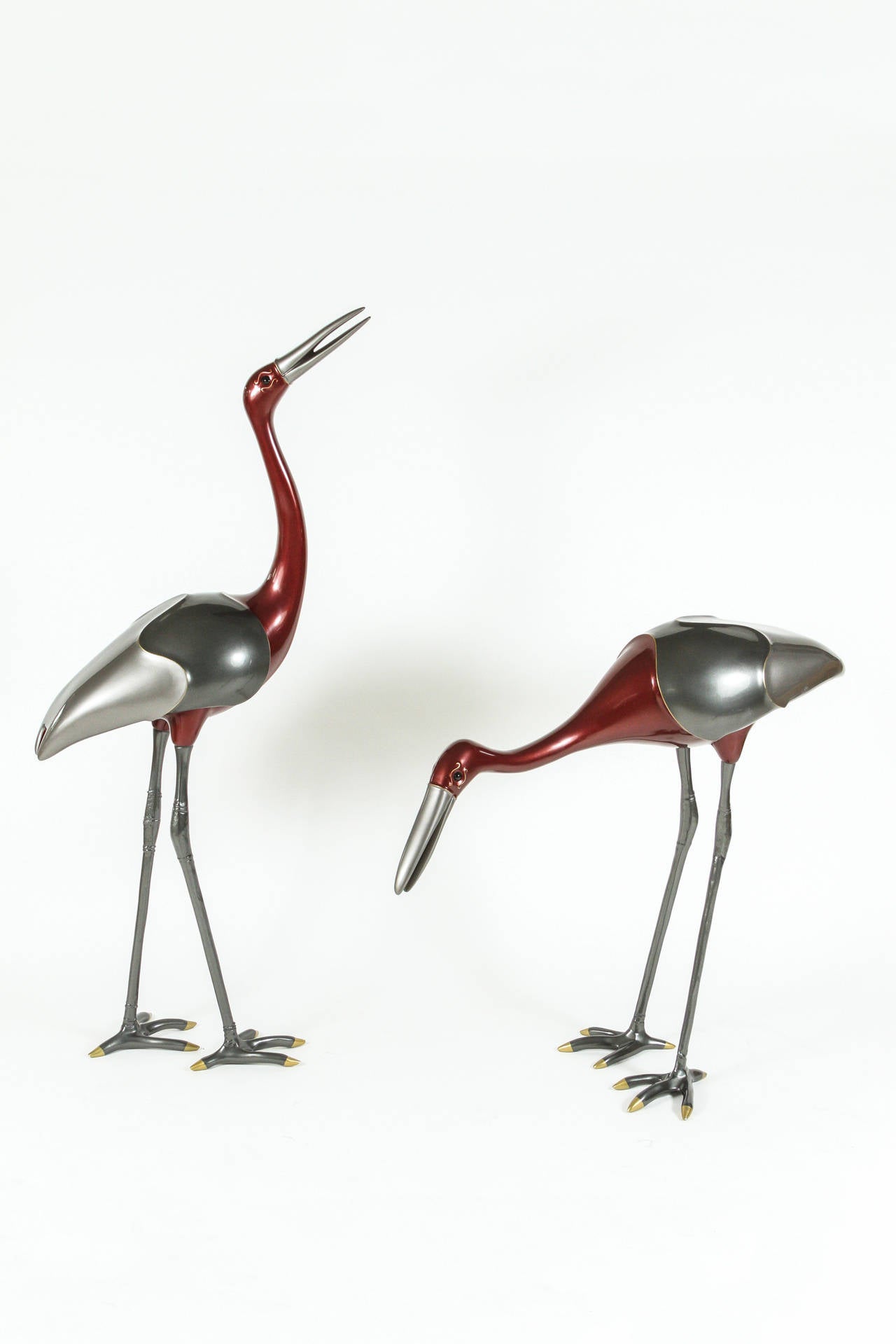 Exceptional pair of cranes in two-toned silver and burgundy enamel with inlaid brass and painted gold details. These pieces have exceptional scale and presence and add a touch of whimsy! Excellent condition with very minor patina to some of the