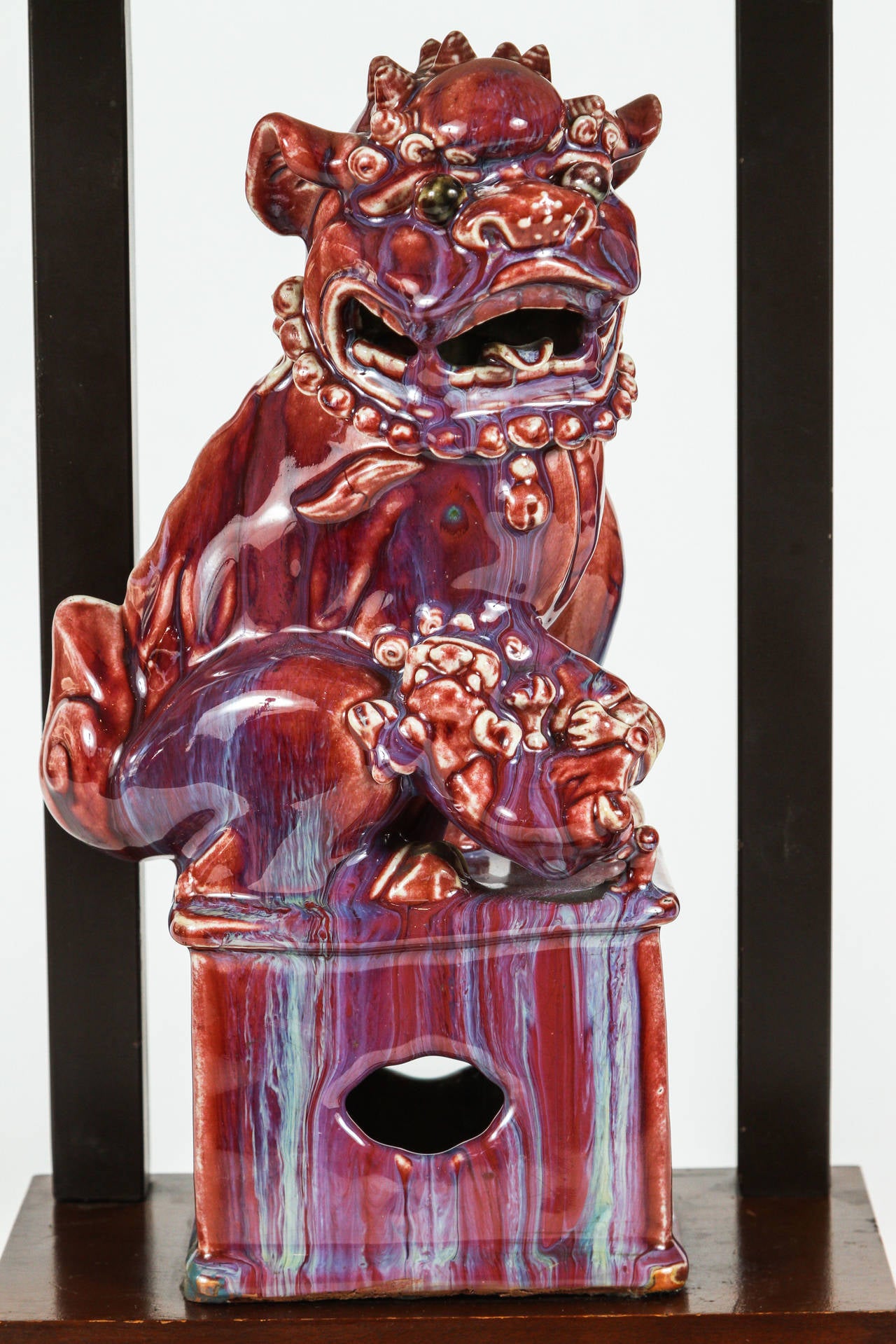 Sophisticated table lamp featuring a ceramic Chinese guardian lion, (known in the west as a foot or temple dog), set on a lacquered armature base. Custom designed by William Haines. Ceramic is glazed burgundy/blue Flambé. Dimensions in listing are