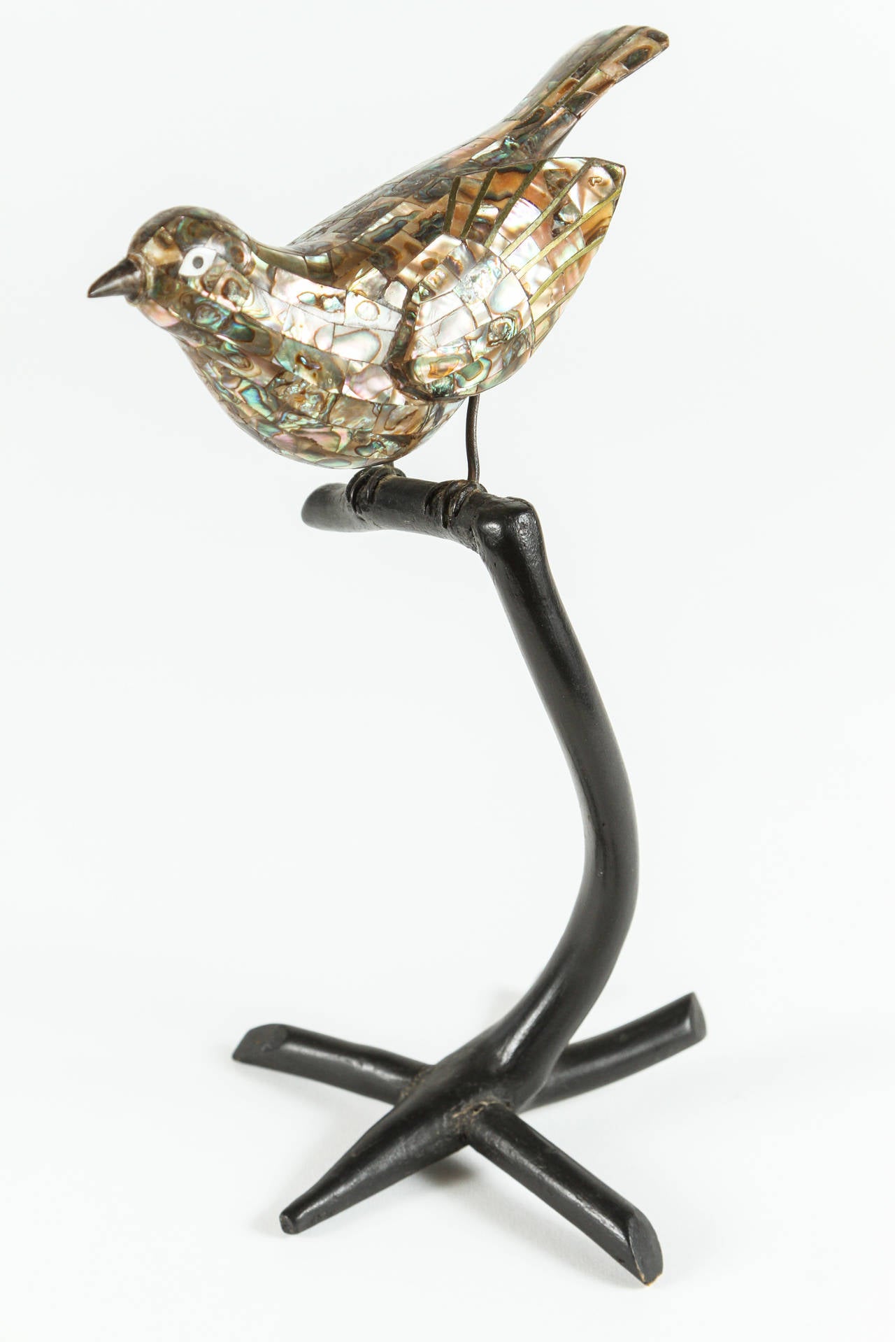 Very unusual bird clad in abalone shell with a metal beak and talons. The detail work is very nicely done and the bird is perched upon a lacquered wooden base.  Made in Mexico by Los Castillo, this bird is unusual for this firm.