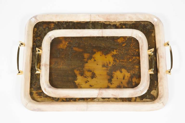 A chic set of two lacquered parchment trays with brass handles and inset with antique mirror with fantastic silver patterns that reveal the wood tray bottom underneath. Dimensions given below are for the larger tray. The smaller tray measures 10.63