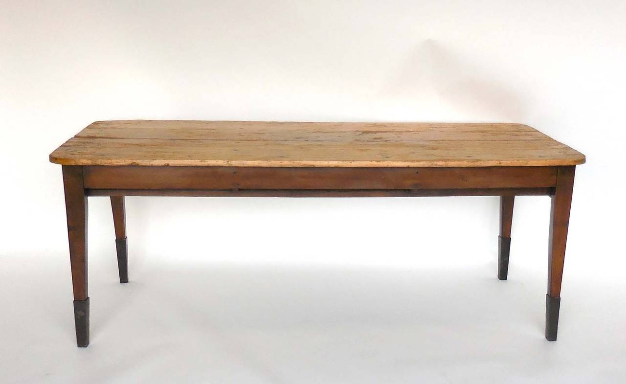 New England pine farm table with forged iron leg bases. A large drawers at each end. One drawer pull is partially broken off but functions well. Four plank top, tapered legs. Shows signs of age and use but has been refurbished. Sturdy and