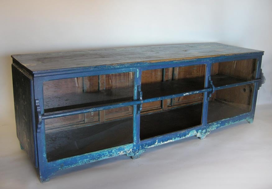 Antique mostrador - store counter, with layers of paint. Glass in front and four operable sliding doors in the back. Worn patina, a beautiful piece of folk art. Works as a buffet or shop counter/display. Would make a great kitchen island!