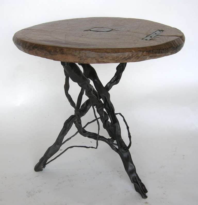 19th c. wooden wheel atop hand forged iron base.  Table top repaired with iron inserts.