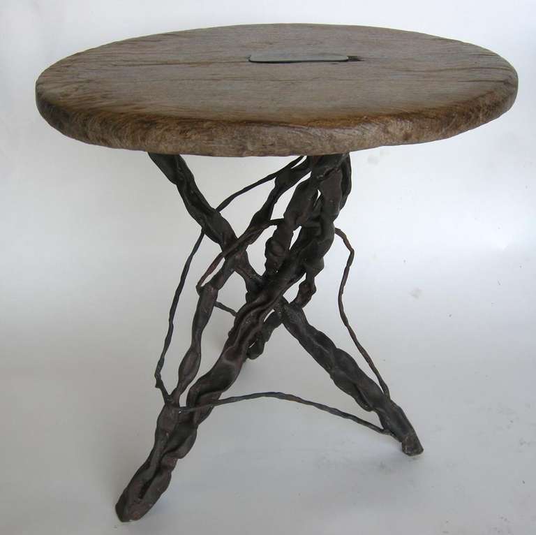 19th century wooden wheel atop a hand-forged grape vine base. Iron inlay in middle of tabletop.