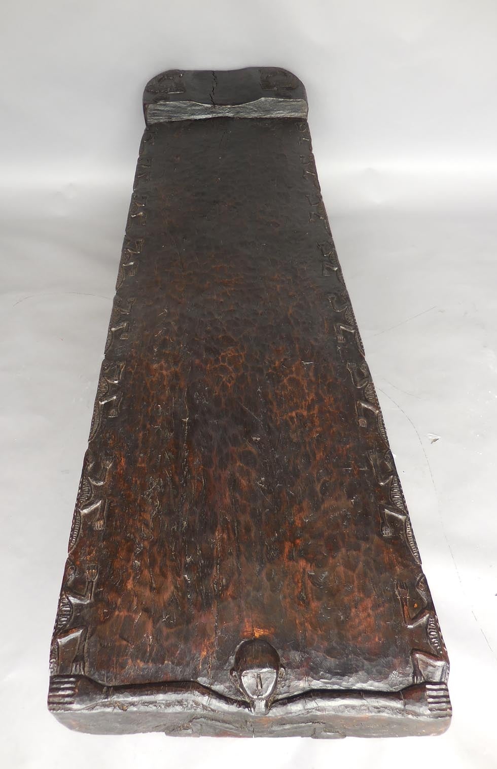 Antique carved bench/wooden bed from Timor Island. Carved lizards along edges and a monkey at the foot. Contemporary hand forged iron base. 
It measures 76.5x20x17H at the seat and 19.75 total height. Hand hewn and hand carved, dark patina.