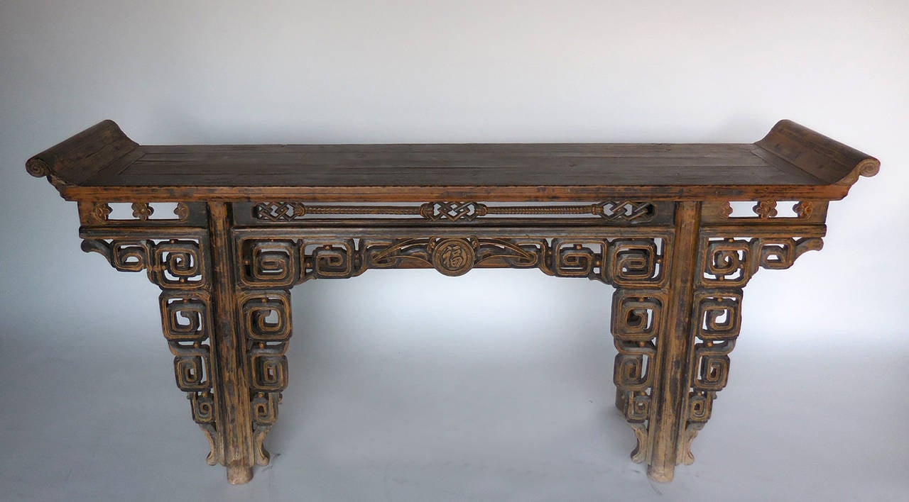 Late 18th century Chinese altar table with intricate geometric carvings throughout. Beautiful old, worn natural patina. Carved sign meaning luck/blessing in the middle front apron. Top finishes in a beautiful upward scroll.