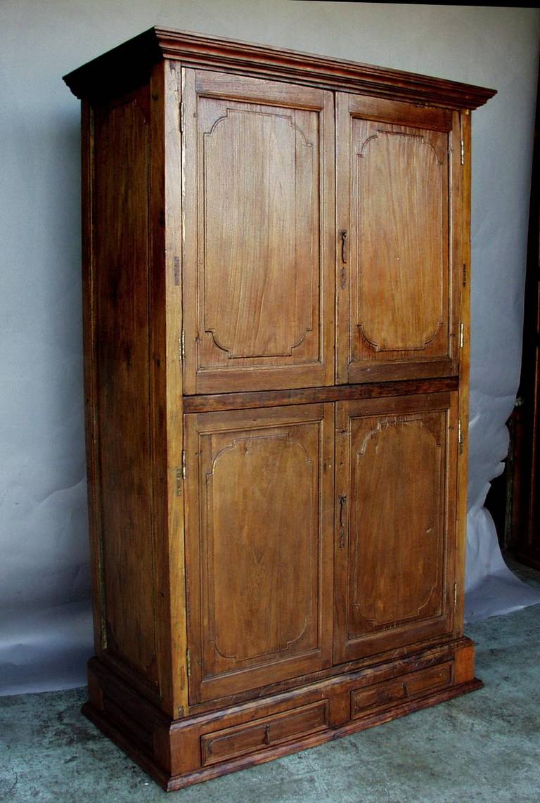 Armoire made from antique doors. The body of the armoire has an upper section with two doors and a lower section with two doors, divided by an interior shelf. The upper section has an additional shelf as well. Lower half is large enough to hold a