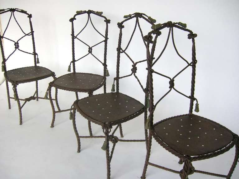 Set of four whimsical wrought iron chairs with traces of old paint. Iron tassels.