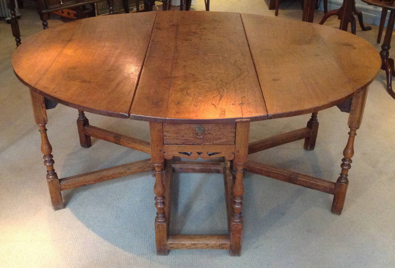 Rare Charles II period oak double gate leg table of generous scale, the richly patinated quarter sawn oak top standing on 12 balustrade turned legs joined by molded stretchers, each end with single drawer over shaped spandrels, the whole with