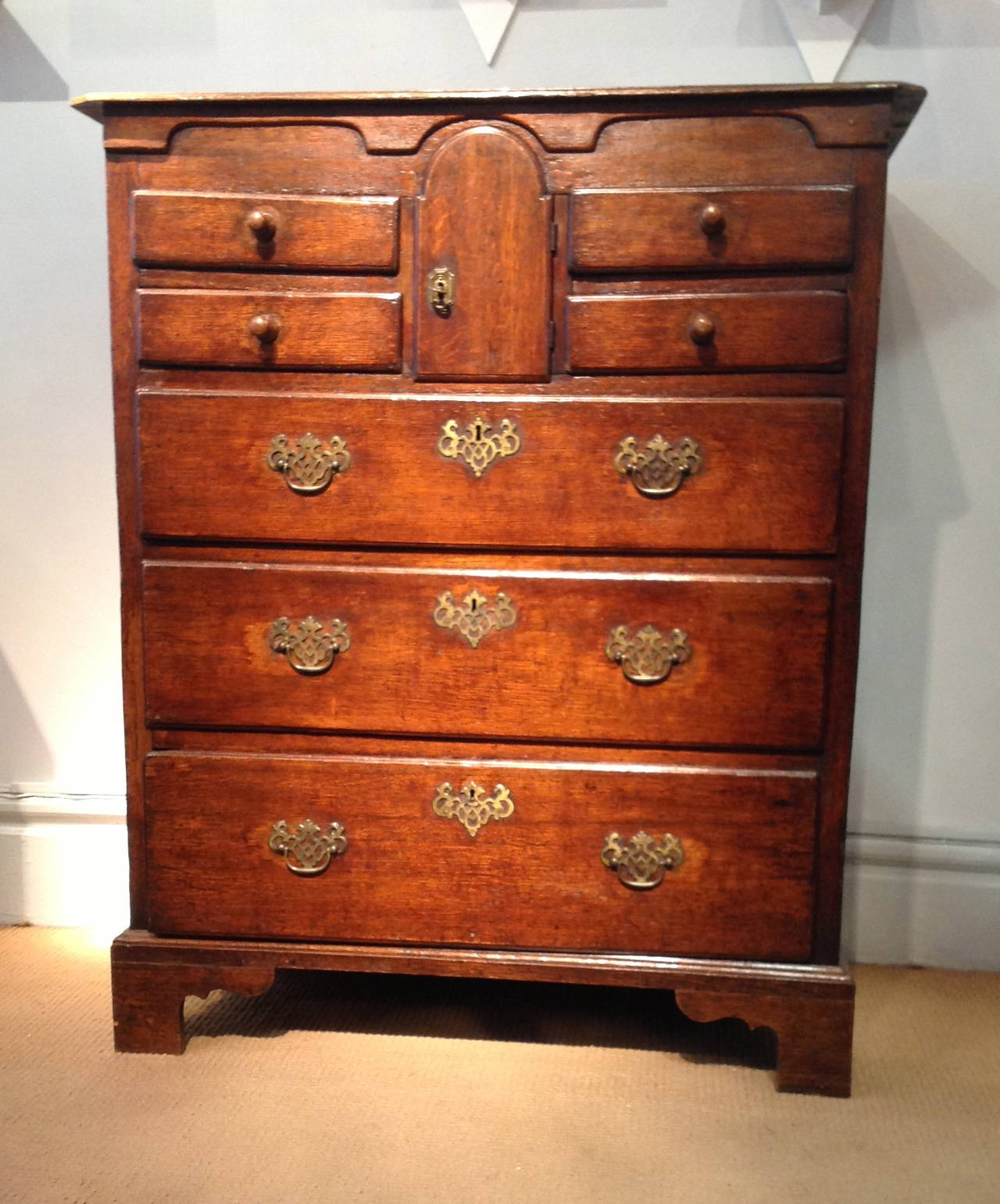 Rare 18th century East Anglian tall chest, the molded top with canted corners over double arch molded front, the central arch panel door flanked by two pairs of small drawers retaining original turned wood knobs over three graduated drawers standing