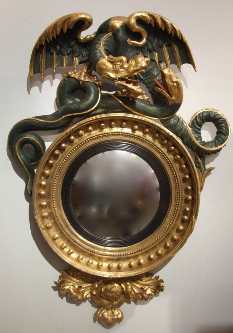 Very fine English Regency convex mirror, the crest with wrestling dragon and serpent, over turned frame with beaded and gilt ball decoration, over foliate carved base, the swirling foliage mirroring the tension exhibited in the cresting, the whole