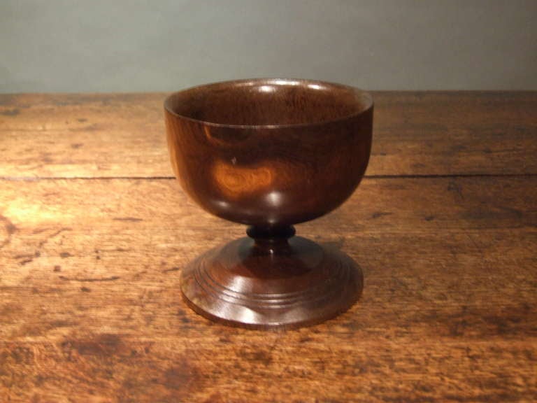 Scottish turned laburnum treenware open footed salt having a goblet form body and footed stem, the whole having good, mellow patina.

While Laburnum grows throughout the United Kingdom, almost all provenanced items fashioned from the timber are of