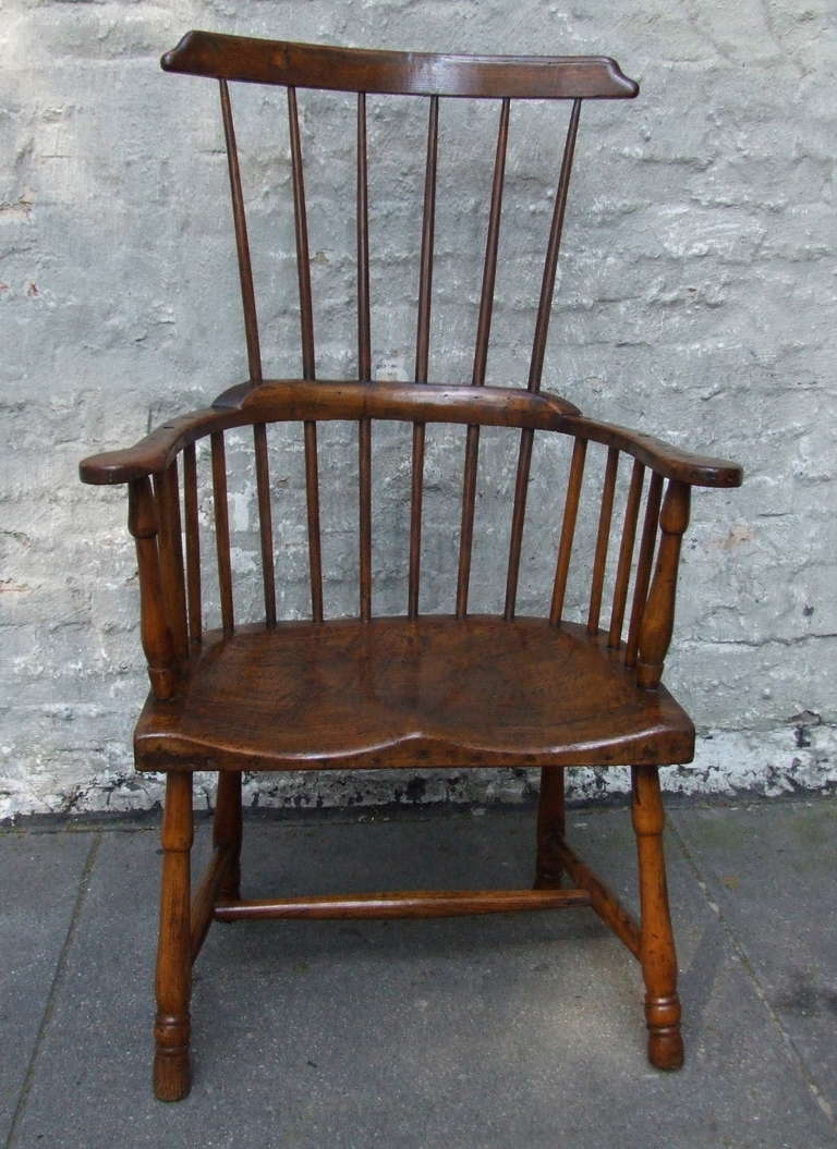 Very good English country comb back Windsor armchair having a generous and deeply saddled seat, the shaped comb back over six spindles joined by continuous curved back rail, over balustrade turned arm supports.  The 