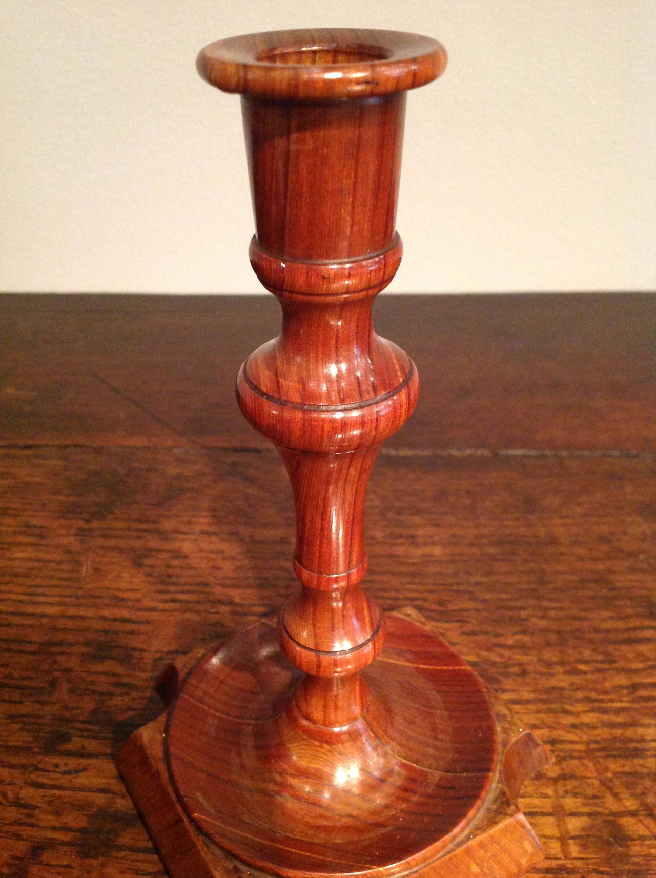 Fine pair of laminated and turned fruitwood candlesticks having dished petal bases with notched corners, having lovely color and patination.