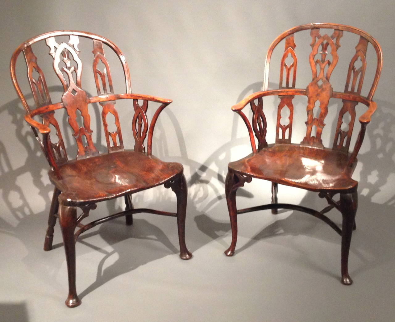 A fine and rare pair of 18th Century yew wood gothic Windsor armchairs having hoop top rails over pierced splats with gothic tracery designs with hoop arms, deeply saddled elm seats over turned rear and cabriole front legs with pierced gothic arch