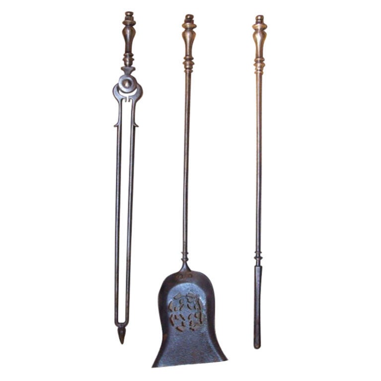 A set of three Georgian firetools in steel with a gunmetal finish comprising tongs, shovel and poker, with turned vase-form finials topped by balls, decorative spurs to poker shafts, and shaped shovel bowl with oval piercework cutout.