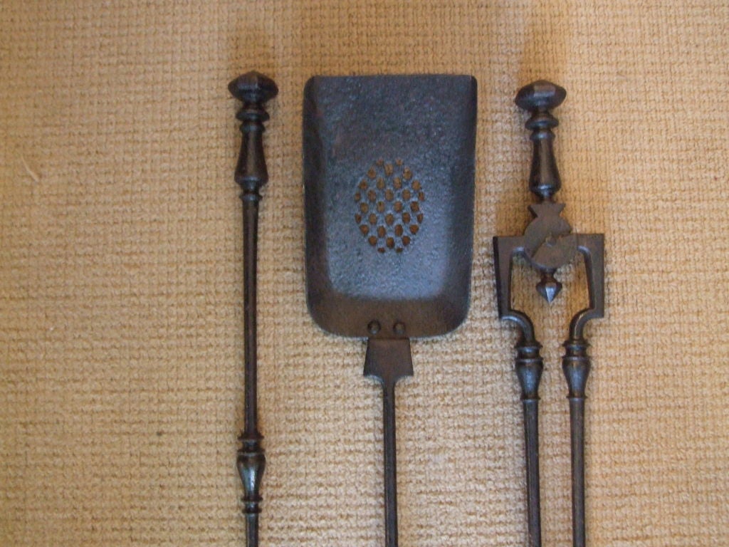 A set of three English Georgian firetools in black iron comprising shovel, poker and tongs having faceted handles on vase form finials with mid-section turnings, the tongs with square shoulders and drop point, and the shovel with square bowl and